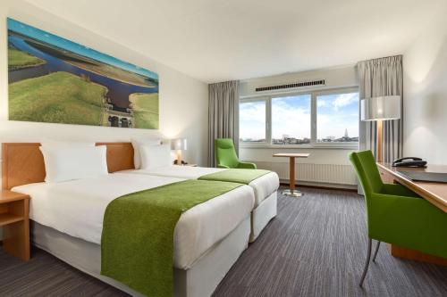 格罗宁根格罗宁根NH酒店的配有一张床和一张书桌的酒店客房