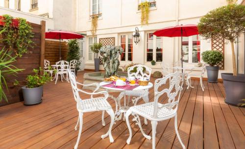 巴黎Agate Hôtel的庭院配有白色的桌椅和红色的遮阳伞。