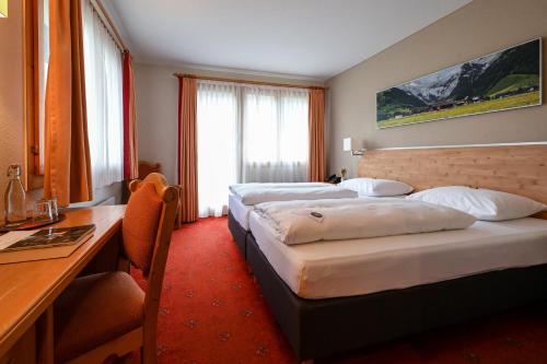 英格堡Hotel Sonnwendhof Engelberg的酒店客房配有两张床和一张书桌