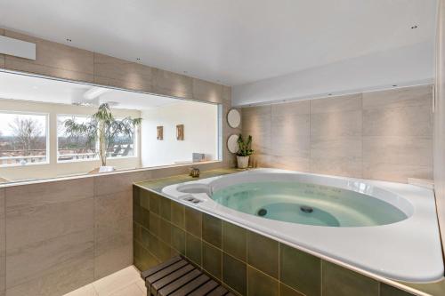 赖特维克勒德秀登酒店的带窗户的浴室内的大浴缸