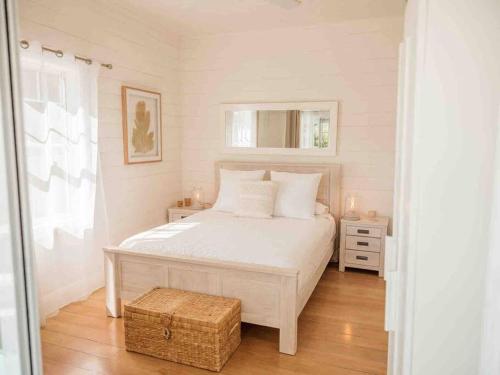 凯阿玛Driftwood Beach House的卧室铺有木地板,配有白色的床。