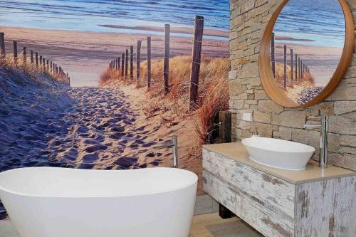 凯阿玛Driftwood Beach House的带浴缸的浴室和海滩绘画