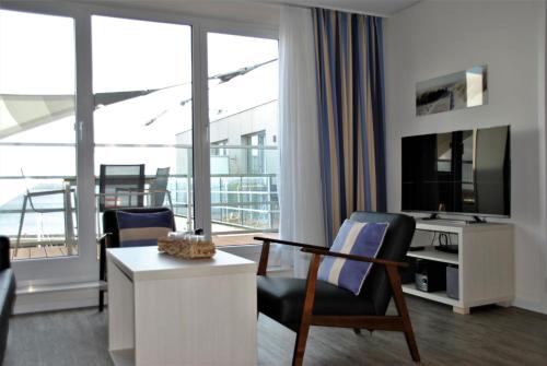 埃肯弗德Apartmenthaus Hafenspitze Ap 42 "Segler", mit Sauna, Blickrichtung offene See - a72332的客厅配有电视、书桌和椅子