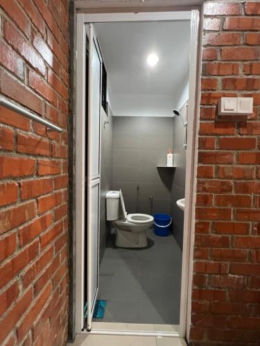 马六甲Ujud Sepakat Homestay的一间带卫生间和砖墙的浴室