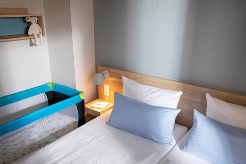 兰图姆TUI BLUE Sylt的一间卧室配有两张带白色床单和蓝色床头板的床。
