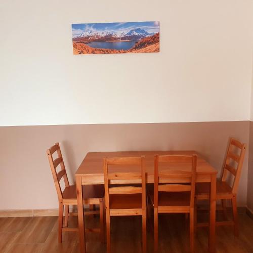 韦切什Airport MicrostorePanzió的餐桌、四把椅子和墙上的绘画