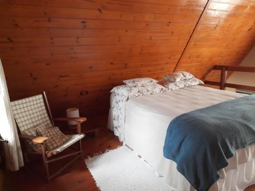 兰舒凯马杜Nosso Pátio - Chalé na Montanha的小屋内一间卧室配有一张床和一把椅子