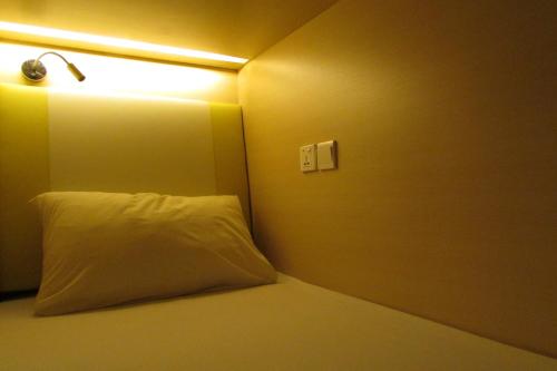 新加坡The Bohemian的一张带白色枕头的床和墙上的灯