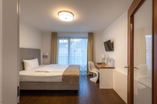 慕尼黑Downtown Vi Vadi Hotel的一间卧室配有一张床、一张书桌和一个窗户。
