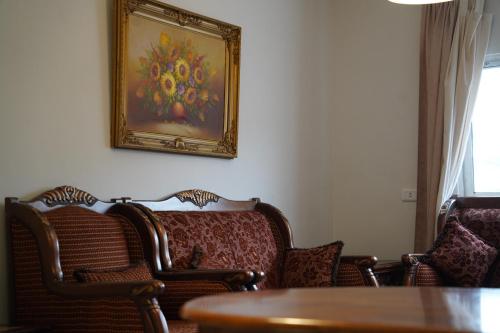 阿杰隆Mahfouz Suite - Ajloun's downtown的一间设有椅子的房间和墙上的绘画