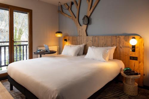 里雾诗ibis Styles Les Houches Chamonix的卧室配有一张白色大床,墙上挂着一棵树