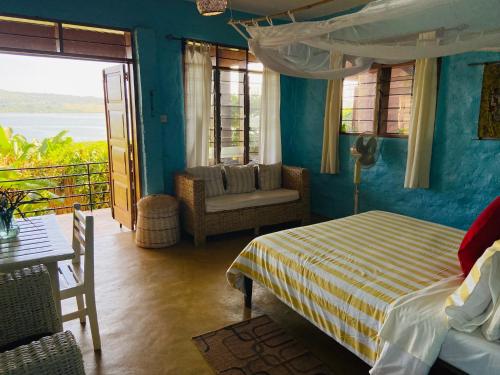 金贾Home On The Nile water front Cottage的卧室配有1张床、1张桌子和1把椅子
