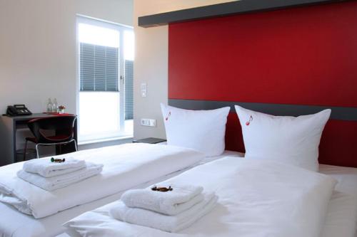 耶拿Hotel VielHarmonie的一间卧室配有两张白色床和毛巾