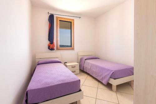 莱乌卡Appartamenti Marinelli - Santa Maria di Leuca的配有紫色床单和窗户的客房内的两张床