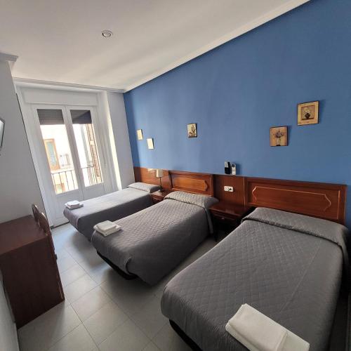 马德里泛美旅馆的一间设有三张床和蓝色墙壁的房间