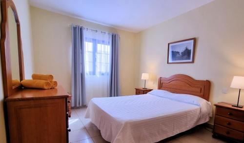 塞博河畔卡莱塔La Graciosa Camelia Beach Vistas Mar的一间卧室配有一张床、一个梳妆台和一扇窗户。