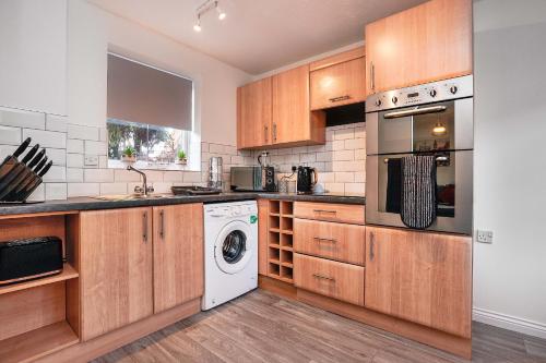 科尔切斯特Victoria Gardens的厨房配有木制橱柜、洗衣机和烘干机