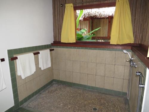 Ile aux Nattes曼尼格里酒店的带淋浴和毛巾的浴室以及窗户。