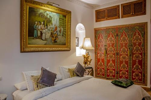马拉喀什Riad Esmeralda的一间卧室设有两张床,墙上挂着一幅画