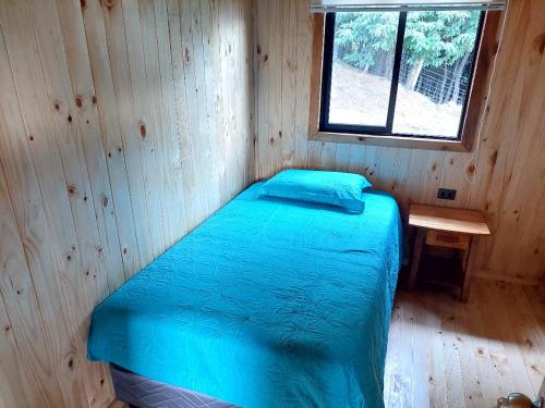 潘吉普伊Cabañas liquiñe Alto的木制客房的一张床位,设有窗户