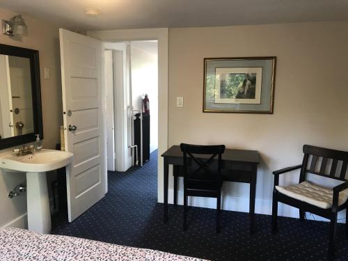温哥华温莎旅馆的一间卧室配有书桌、水槽和床。