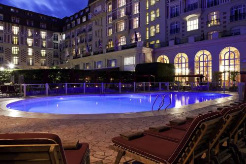 多维尔多维尔皇家吕西安巴里亚酒店的一座大楼前的游泳池