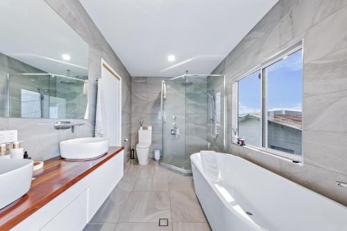埃尔利海滩Nautical Views - Airlie Beach的浴室配有2个盥洗盆、浴缸和淋浴。