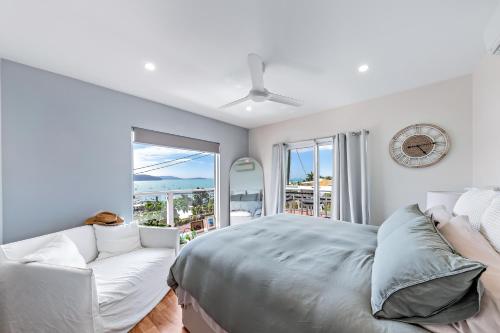 埃尔利海滩Nautical Views - Airlie Beach的一间卧室配有一张床、一张沙发和一个时钟