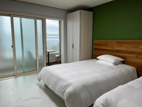 济州市Hill Hotel的一间卧室设有两张床和绿色的墙壁
