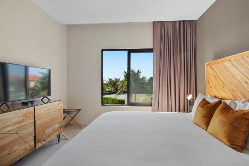 MalmokGold Coast Aruba - Aurum Collection的白色卧室设有一张大床和电视。