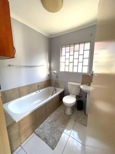比勒陀利亚Are you travelling to Pretoria?的带浴缸、卫生间和盥洗盆的浴室