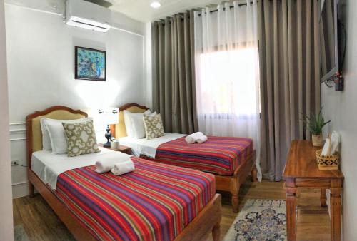 Bayubay SurVilla Lydia y Jose Heritage Hotel的酒店客房设有两张床和窗户。