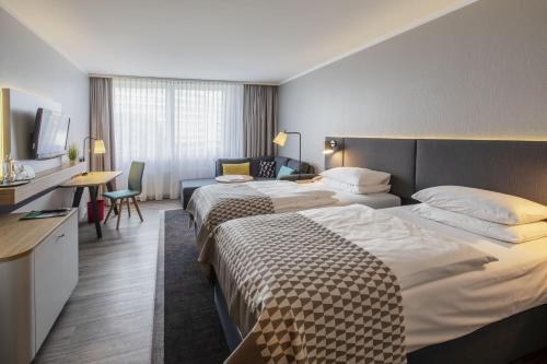 诺伊斯Holiday Inn Düsseldorf-Neuss, an IHG Hotel的酒店客房设有两张床和电视。