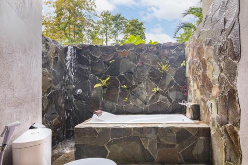 美娜多Thalassa Dive & Wellbeing Resort Manado的一间带石墙和浴缸的浴室