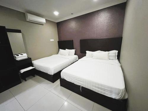 怡保射手座酒店的酒店客房,配有两张带白色床单的床
