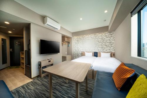 东京KOKO HOTEL Residence Asakusa Kappabashi的一间酒店客房,配有一张床铺、一张桌子和一台电视