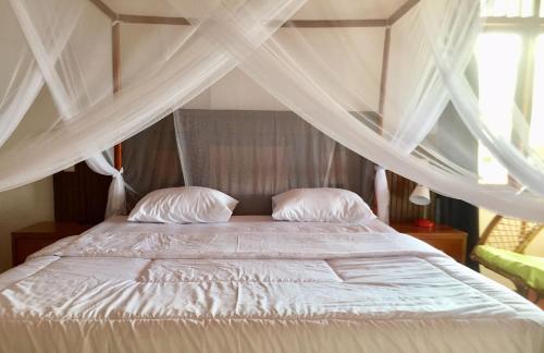 图克图克Toba Sunset的卧室内的一张带白色床单和枕头的床