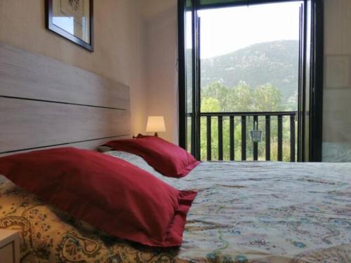 普拉德埃米塔Apartamento con jardín y luminoso Besiberri 6的一间卧室配有一张带红色枕头的床和一扇窗户