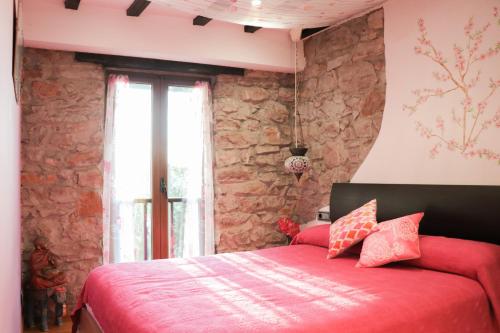 莱索Apartamento Jaizkibel by SanSe Holidays的一间卧室设有红色的床和石墙