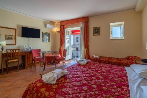 锡拉库扎地中海酒店的酒店客房带一张床、一张桌子和椅子