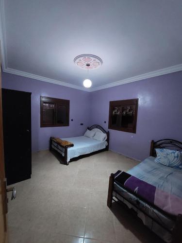 达赫拉RESIDENCE ABOU YASSINE的紫色墙壁客房的两张床
