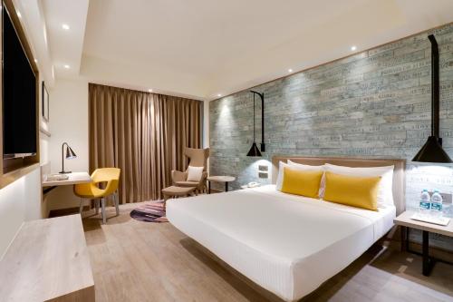 孟买Lemon Tree Premier, Mumbai International Airport的卧室配有白色大床和砖墙