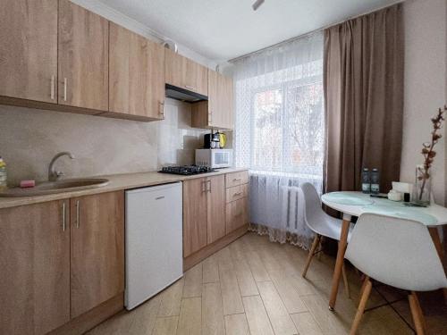 伊万诺-弗兰科夫斯克Апартаменти по вул Галицька的厨房配有木制橱柜和1张带白色冰箱的小桌子。