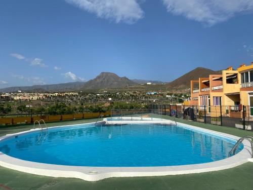 洛斯克里斯蒂亚诺斯Simon beach house Los Cristianos的一座大型蓝色游泳池,位于一座建筑的顶部