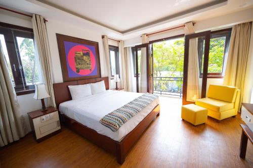 会安Fuse Old Town Hoi An的一间卧室配有一张床、一把椅子和窗户。