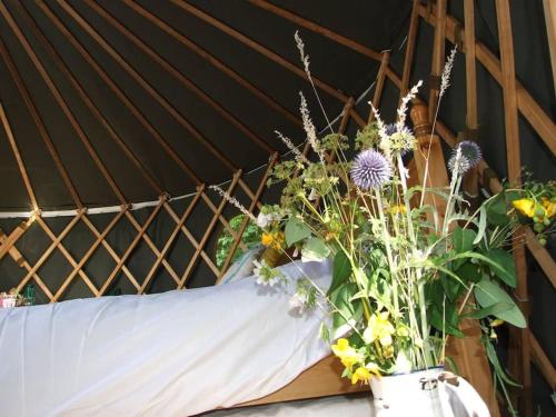 芬赫斯特'Oak' Yurt in West Sussex countryside的床上方装满鲜花的花瓶