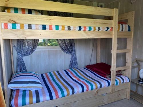 Le ViganGîte pèlerin - "Les Sources" - Chambres Dortoirs的一张带彩色条纹床单的木制双层床