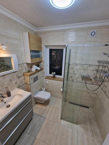 韦巴Apartamenty Polanki 2 - Sauna, Jacuzzi, Podgrzewany Basen的带淋浴、卫生间和盥洗盆的浴室