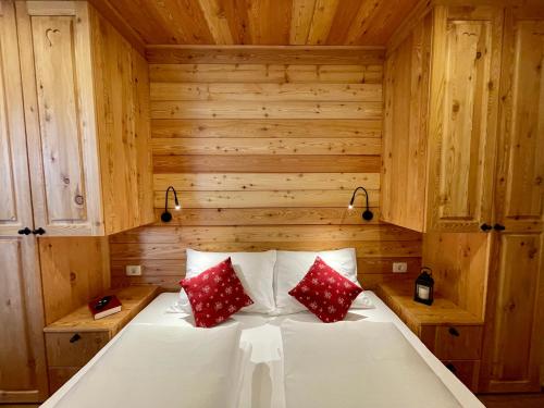 克拉尼斯卡戈拉Hotel ŠURC的木制房间的一个床位,配有两个红色枕头