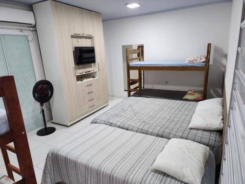 巴雷里尼亚斯BARREIRINHAS CHALÉ 12 PORTO DOS LENÇÓIS的客房设有两张床、一张桌子和一台电视机。